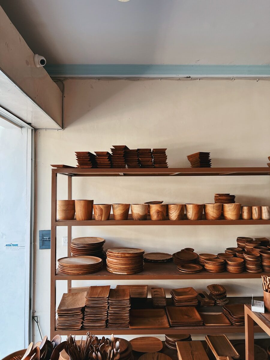 A display of various wooden dishes and utensils on shelves, showcasing bowls, plates, and serving platters in a warmly lit shop setting.
