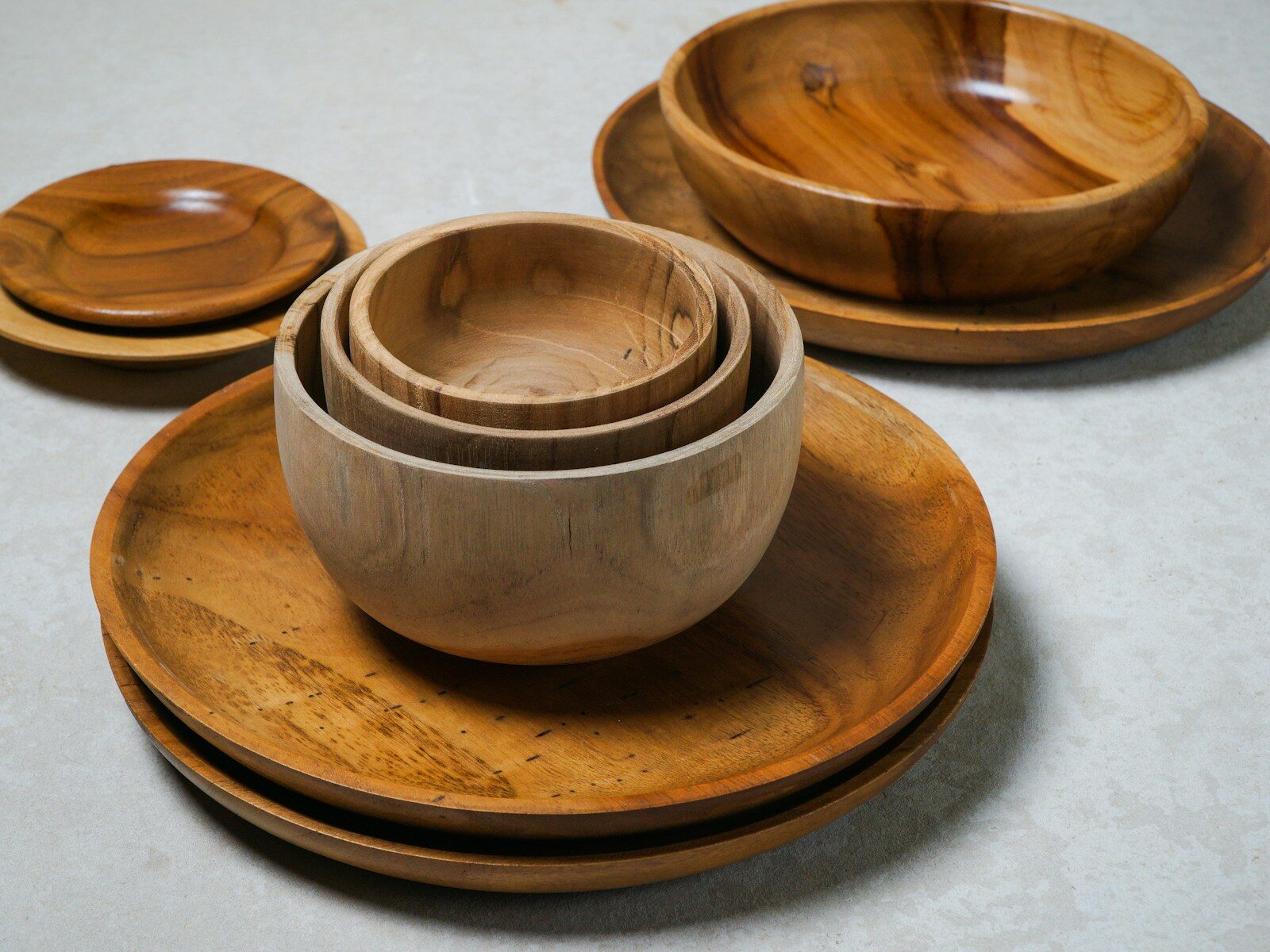 Stacked wooden bowls and plates in various sizes showcase natural wood grain, emphasizing eco-friendly dining aesthetics. Ideal for kitchen decor.