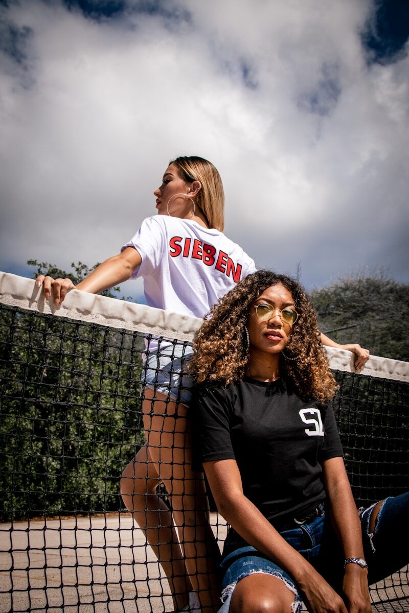 woman in black and white jersey shirt standing beside fence during daytime